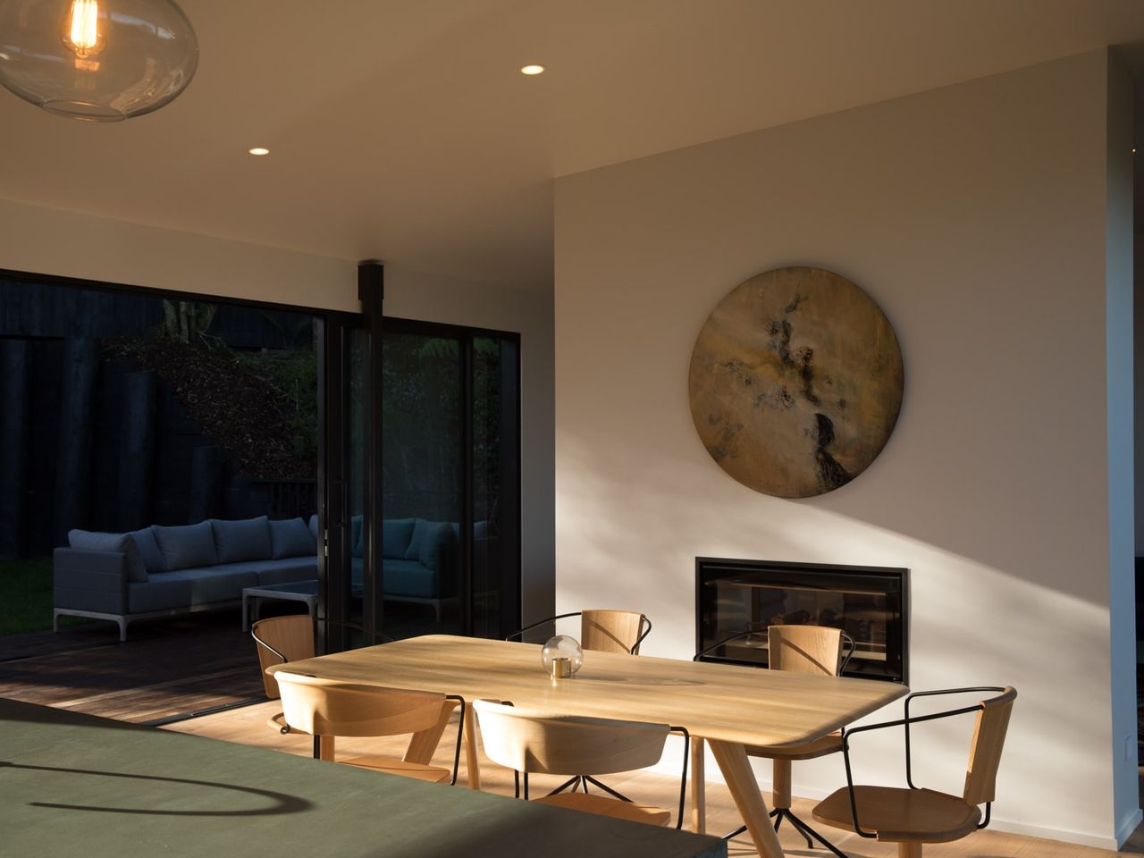 Interior dining area at Tree Tops House with modern furniture, a fireplace, and outdoor access to bushland.