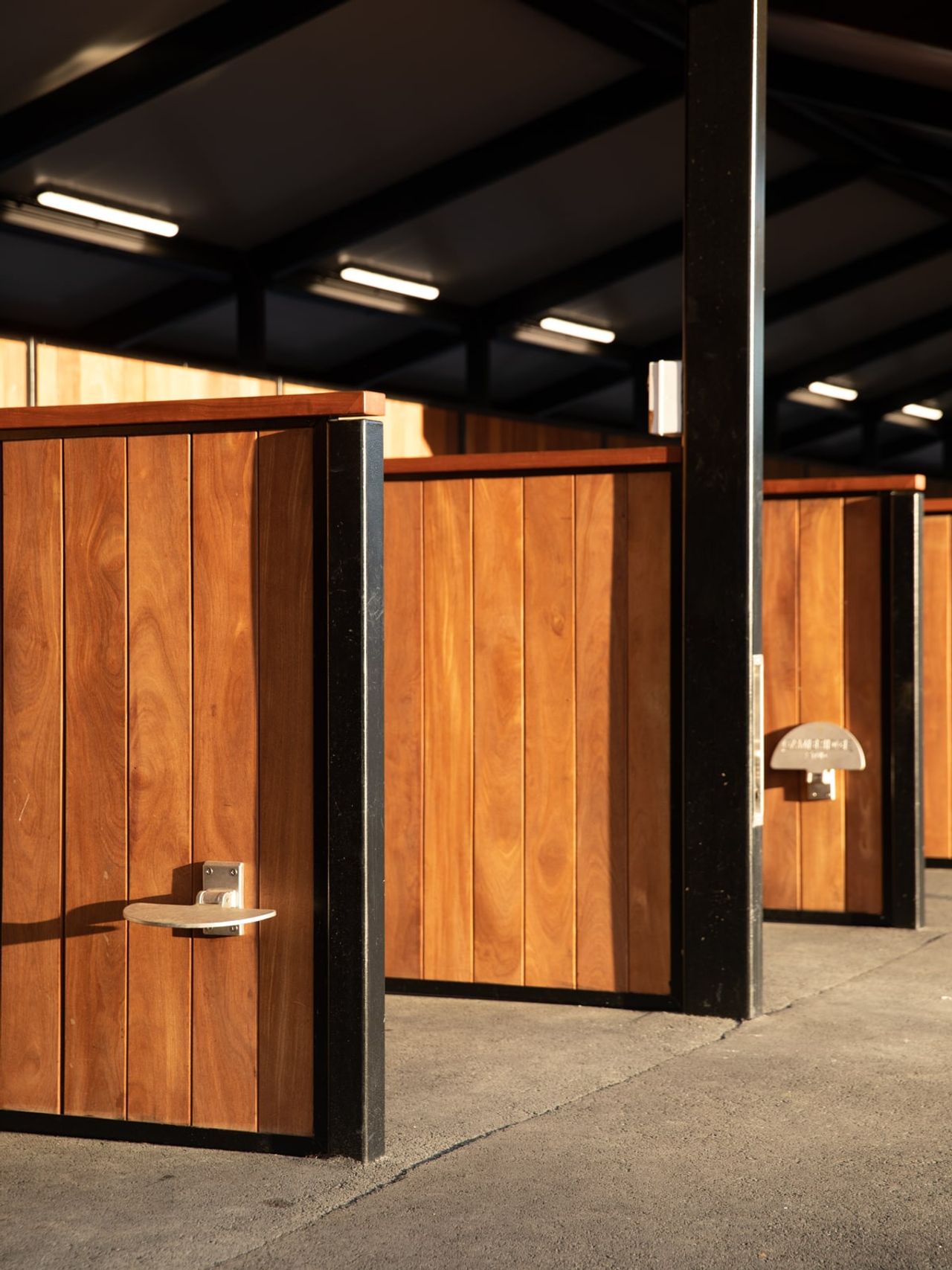 Close-up of wooden horse stall doors with steel framing and feed trays at Auckland Racing Club stables, Ellerslie
