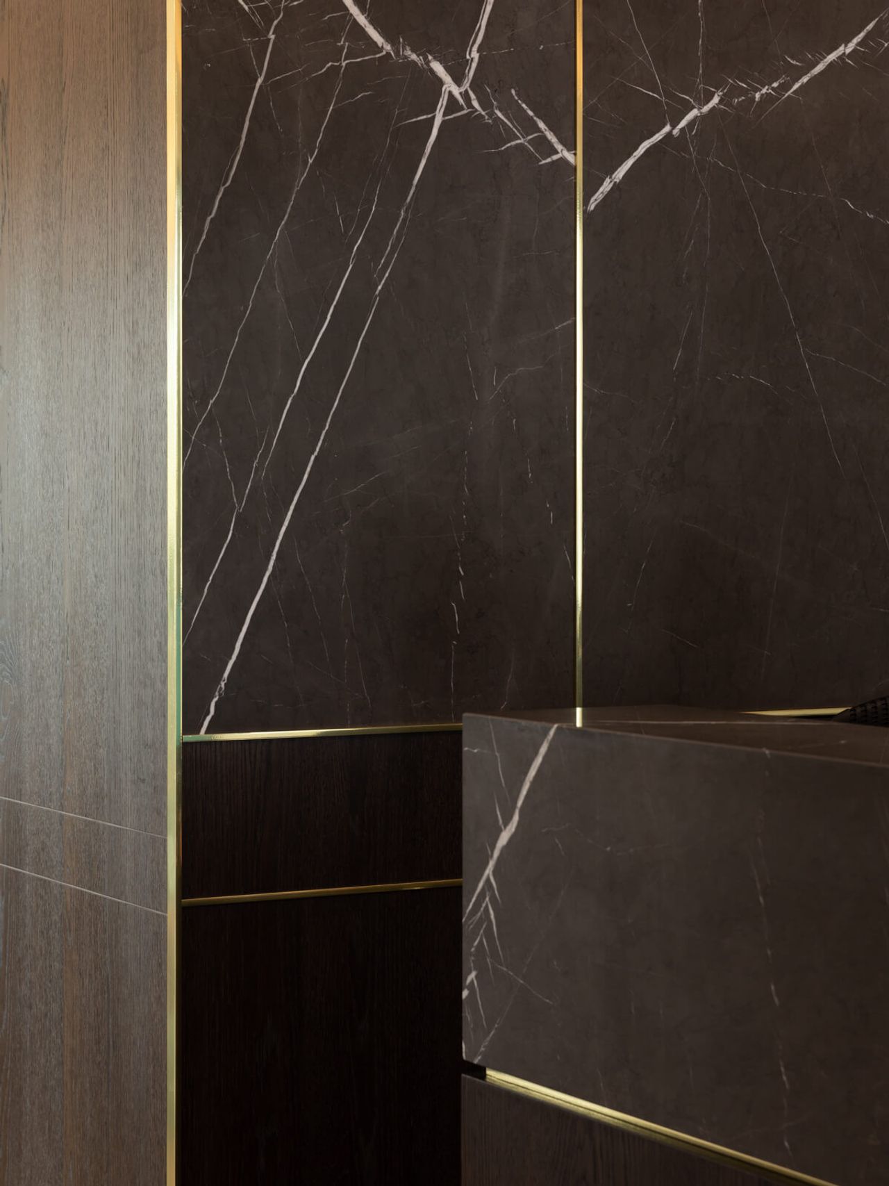 Luxury interior detail of Cambridge Stud Farm hospitality space featuring dark marble with white veining, gold accents, and warm wood paneling, showcasing high-end architectural design and premium interior finishes in New Zealand.