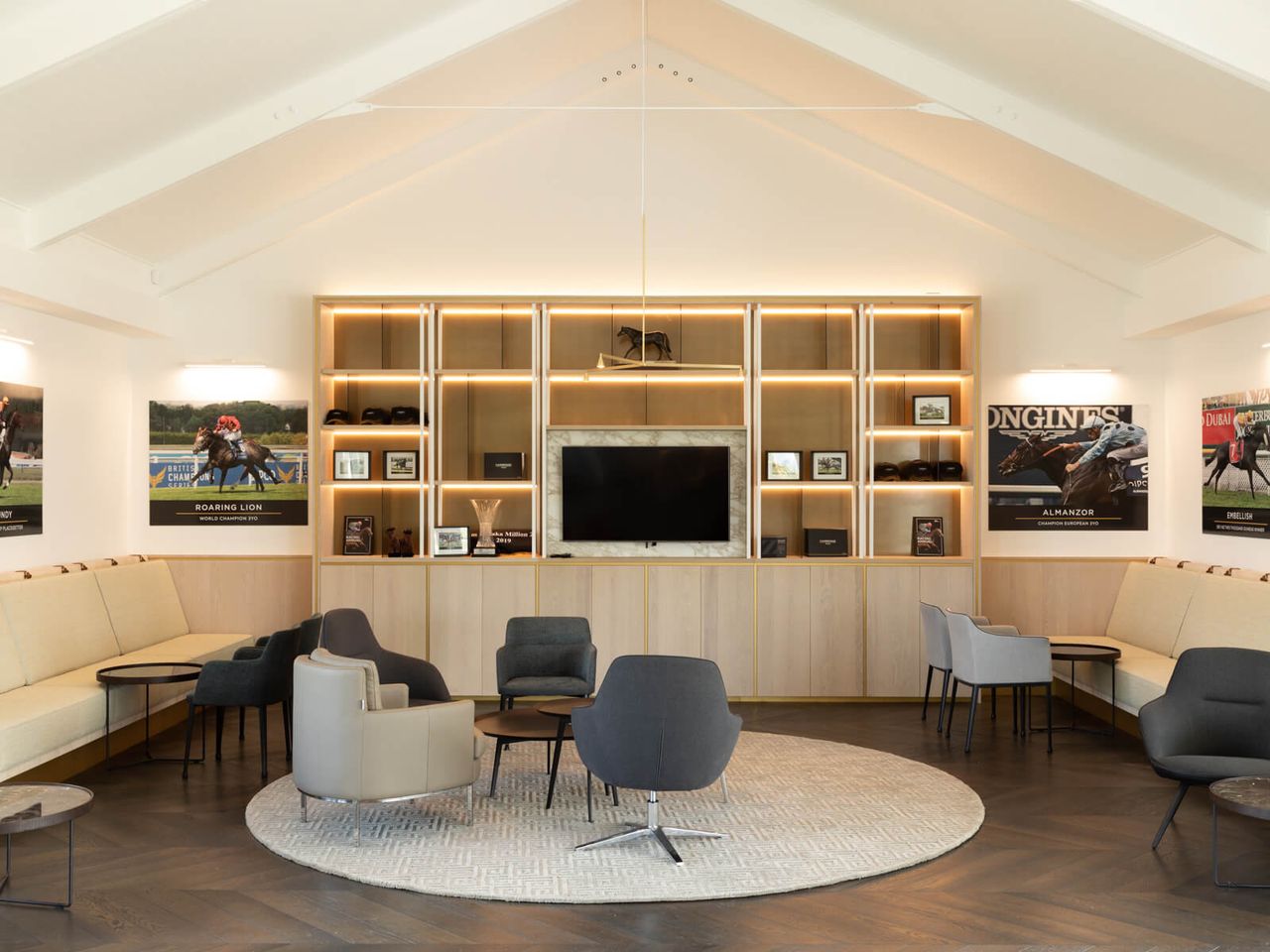 Modern lounge area at Cambridge Stud Farm featuring equine-inspired architecture, with backlit shelving, comfortable seating, and horse racing memorabilia, reflecting a luxurious yet functional design for hospitality and equestrian enthusiasts in New Zealand.