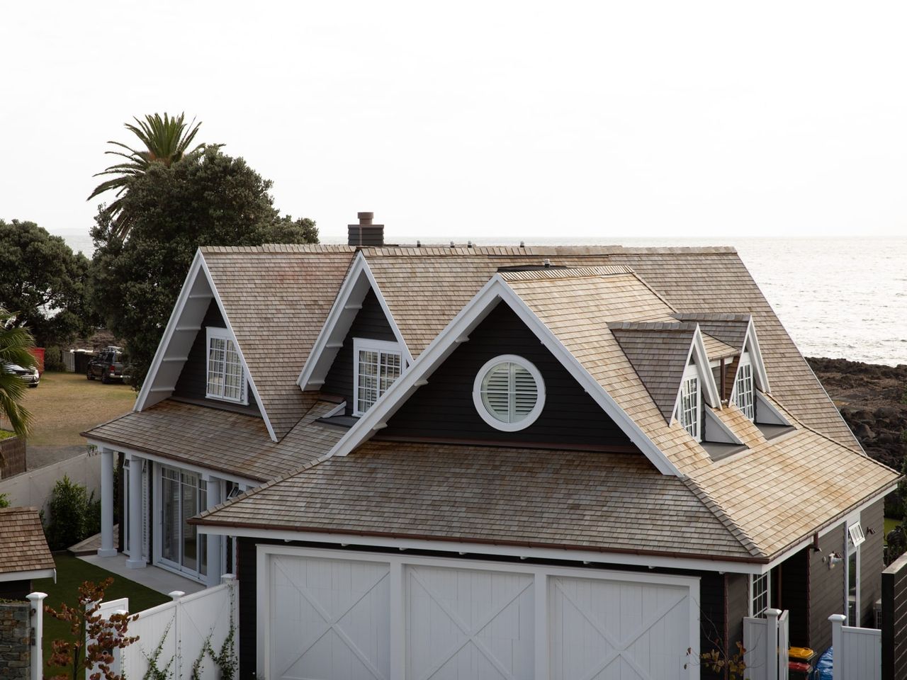 Exterior view of an award-winning Cape Cod home in Milford, showcasing cedar shingles, white trim, and oceanfront location.