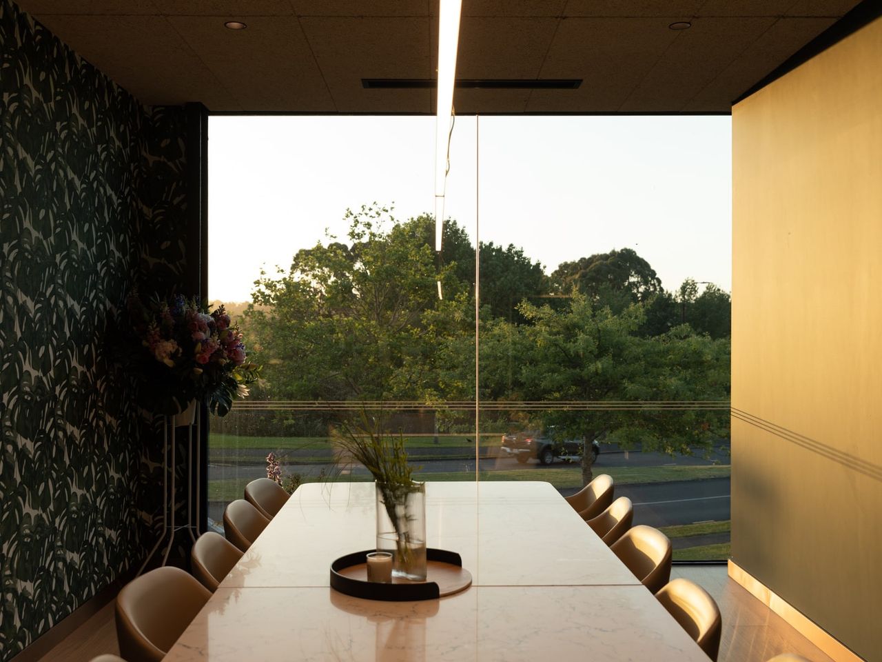 Interior view of Fields Cafe by OKLA, featuring a sleek marble table, modern decor, and expansive glass windows with views of lush greenery, showcasing contemporary interior design in New Zealand.
