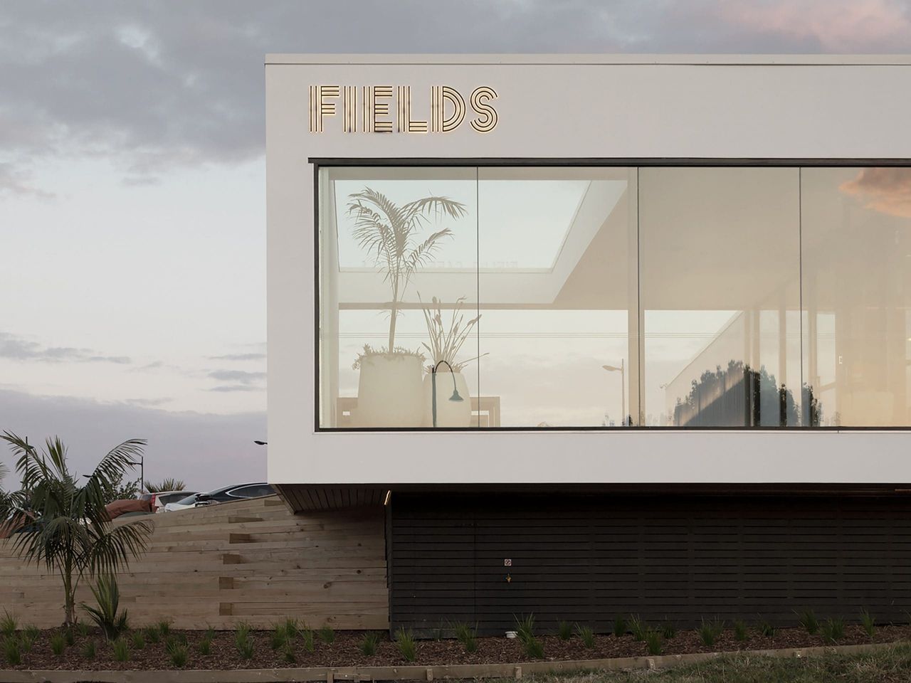 Close-up of Fields Cafe by OKLA, showcasing contemporary architectural design with large glass windows, natural landscaping, and a modern hospitality aesthetic in New Zealand.