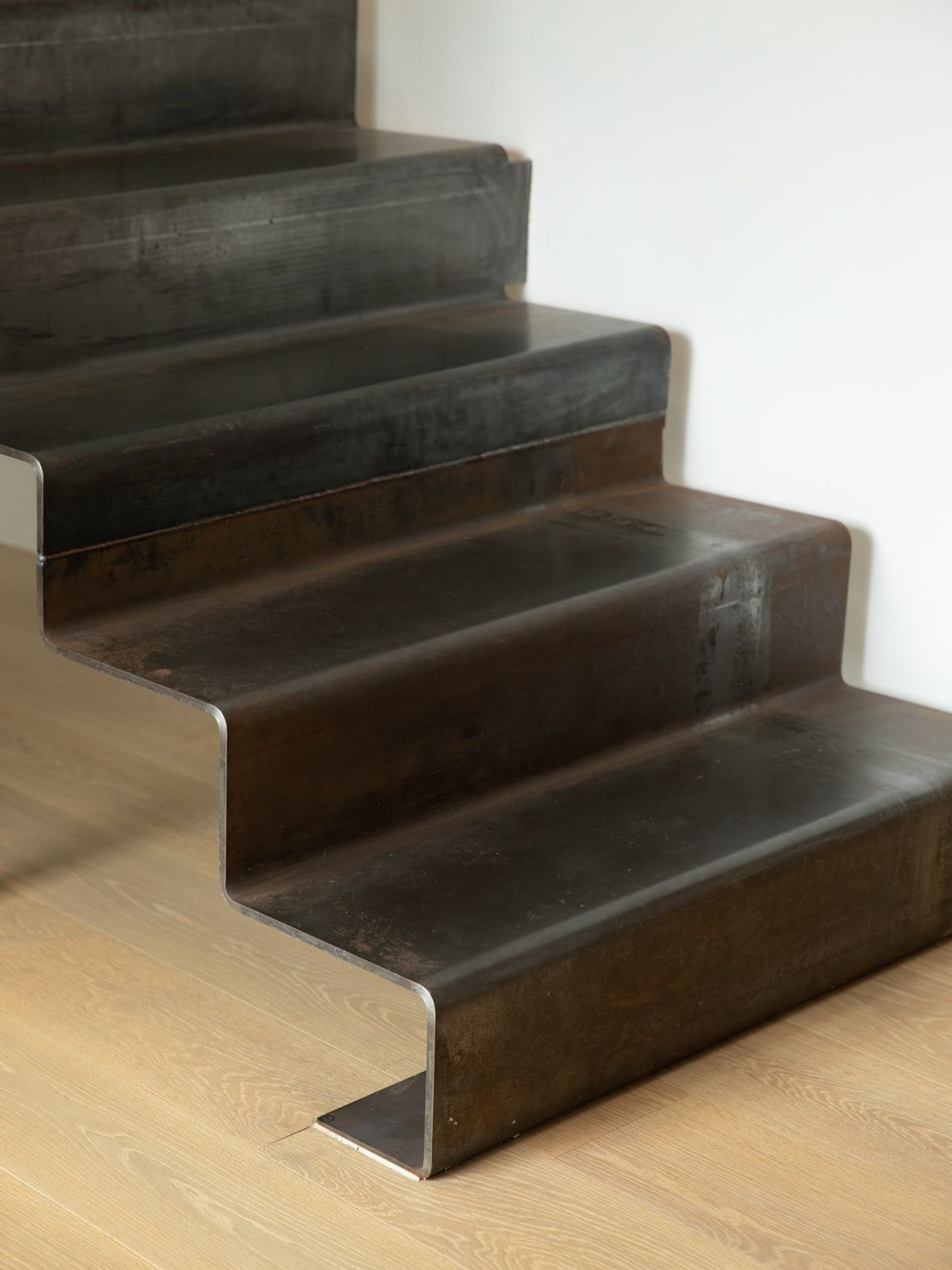 Detail of custom metal staircase in the Karaka Lake Showhome, featuring industrial-inspired design and seamless integration with timber flooring. Showcasing innovative architectural design by Young+Richards+ in New Zealand.