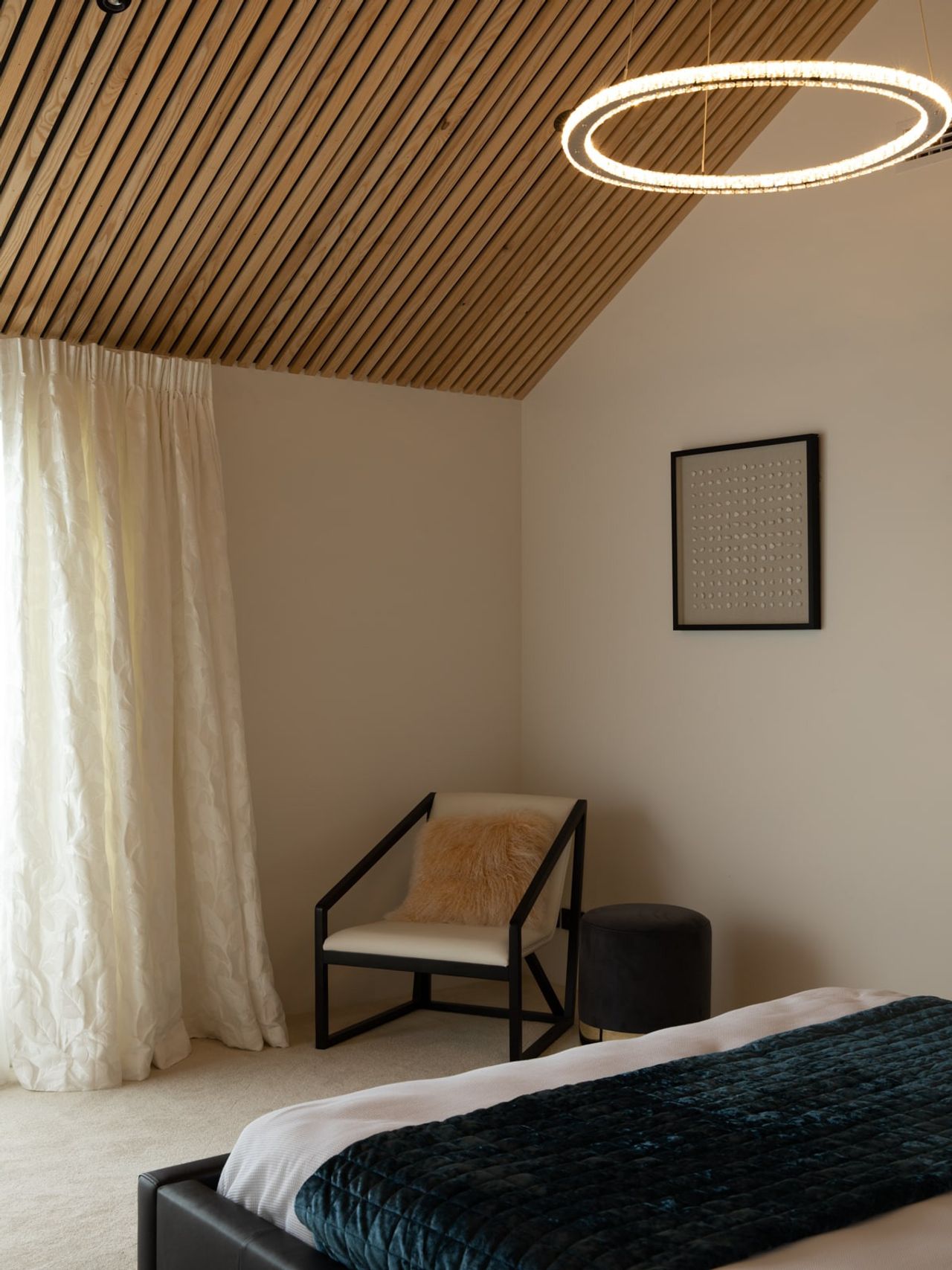Modern bedroom in the Karaka Lake Showhome featuring a slatted timber ceiling, elegant pendant lighting, and minimalist decor. This serene space exemplifies premium interior design and architectural craftsmanship by Young+Richards+ in New Zealand.