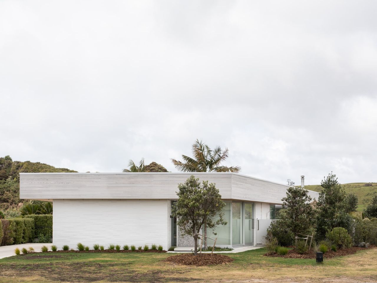 Modern Beach Pad exterior, a sleek contemporary beachside home with white cladding, glass walls, and mid-century modern influences