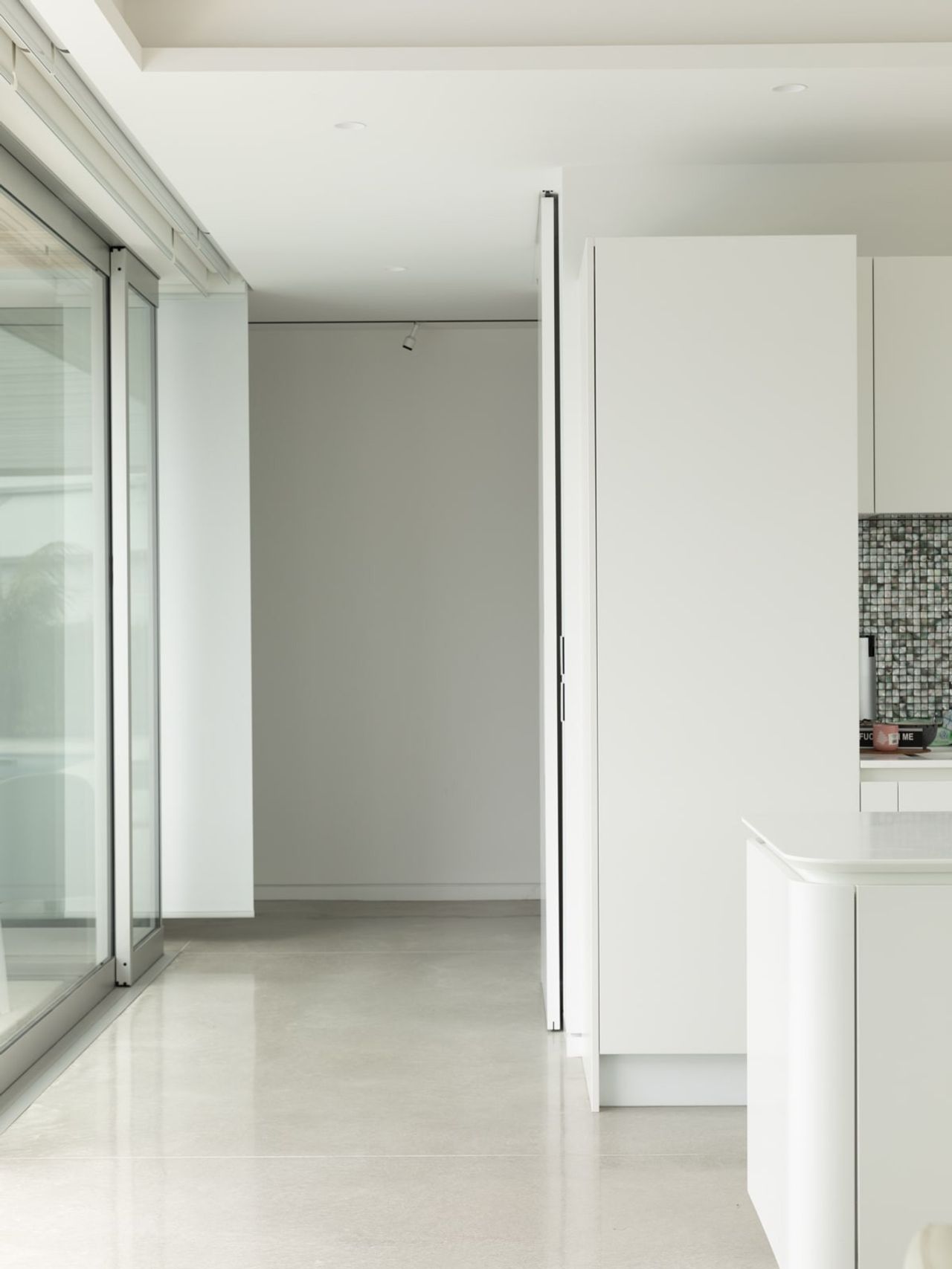 Minimalist interior of the Modern Beach Pad with polished concrete floors, sleek white cabinetry, and glass sliding doors.