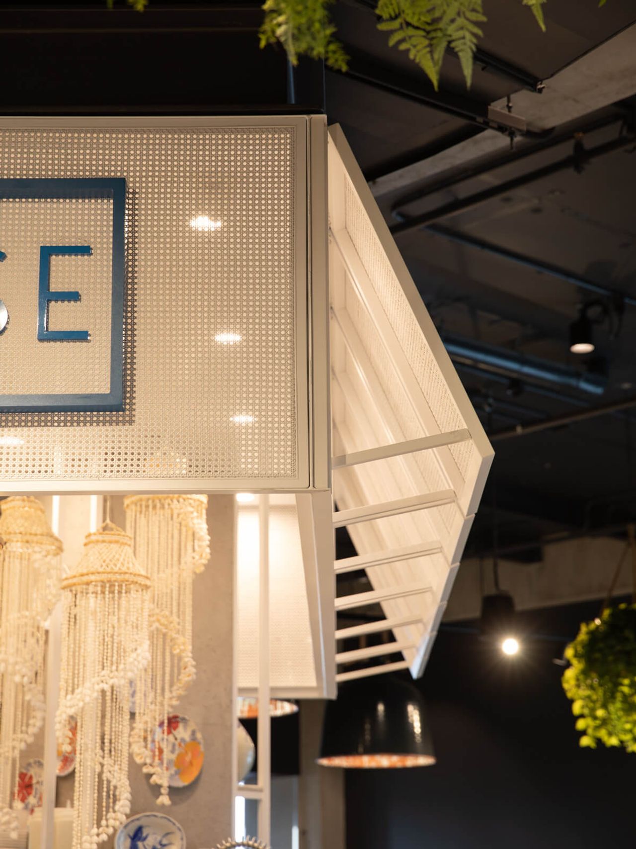 Detailed view of Poke House restaurant’s modern design, featuring perforated metal paneling, hanging shell chandeliers, and decorative plates. A creative blend of contemporary and coastal-inspired interior design in Auckland.