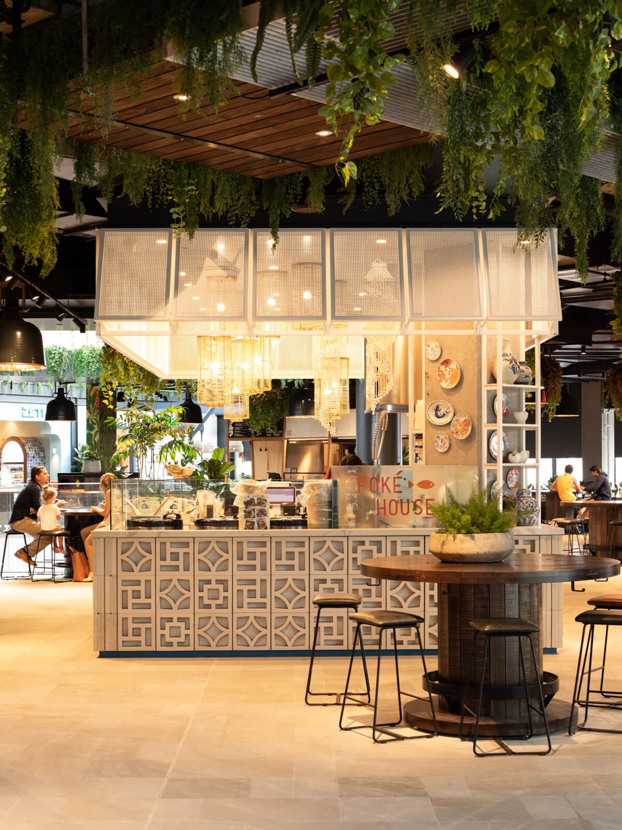 Poke House restaurant in Westfield Mall, featuring intricate patterned counters, lush greenery, warm lighting, and cozy seating areas. A perfect example of innovative hospitality and interior design in Auckland.